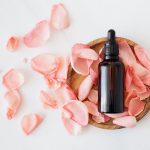 composition of cosmetic bottle with pink rose petals and wooden plate