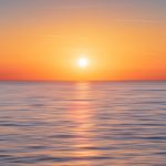 calm water with sun and orange sky